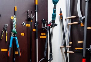 On the wall at the end of the screws hang various tools, e.g. pliers, secateurs, trowels, cordless trimmers, etc.